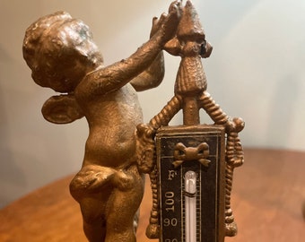 A wonderful antique thermometer with a cherub and the original working thermometer.