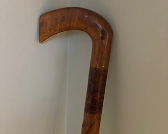 May include: A wooden walking stick with a carved handle and a decorative pattern down the shaft.