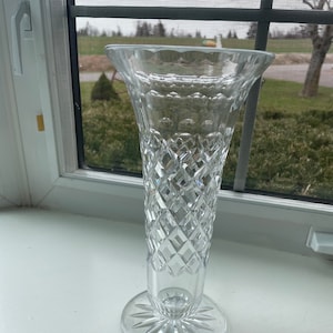 May include: A clear glass vase with a diamond pattern. The vase has a wide mouth and a narrow base.