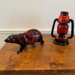 May include: A red and black ceramic bear figurine and a red and black ceramic lantern vase. Both items have a mottled glaze.