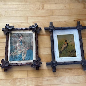 May include: Two rectangular dark brown wooden frames with carved leaf accents at the corners. The left frame contains a print of a person in a blue dress and floral shawl. The right frame holds a print of a bird with an orange neck patch.