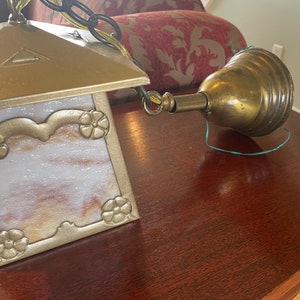 May include: A gold and white stained glass ceiling light fixture with a brass chain and a brass bell-shaped canopy.