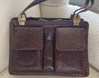 Peut inclure: Un sac à main en cuir marron avec un motif en peau de serpent et deux poignées supérieures. Le sac a deux grandes poches sur le devant.