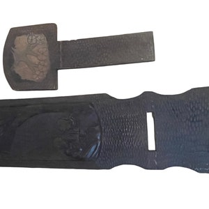 May include: Two wooden shoe horns with carved designs. The larger shoe horn has a carved design of a tree with leaves and flowers. The smaller shoe horn has a carved design of a bird.