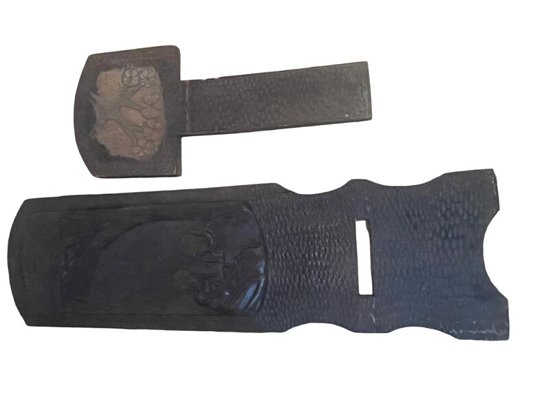 May include: Two wooden shoe horns with carved designs. The larger shoe horn has a carved design of a tree with leaves and flowers. The smaller shoe horn has a carved design of a bird.