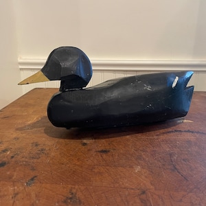 Unusual chip carved antique floater black duck decoy with a weight on the bottom.