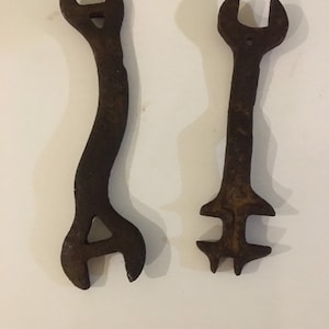 May include: Two rusty wrenches with different shapes and sizes. The wrenches are made of metal and have a dark brown colour.