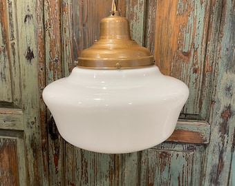 May include: A white glass pendant light fixture with a brass finish. The light fixture is hanging from a chain.