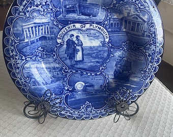 May include: Blue and white ceramic plate with a decorative border and images of historical landmarks in Plymouth, Massachusetts. The plate reads "Souvenir of Plymouth" and features images of the Peregrine White Cradle, Elder Brewster Chair, Pilgrim Hall, the Return of the Mayflower, and the Mayflower in Plymouth Harbour.