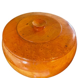 Könnte beinhalten: Eine runde Holzkiste mit Deckel. Die Kiste ist aus hellbraunem Holz mit natürlicher Oberfläche. Der Deckel hat einen kleinen Knopf oben.