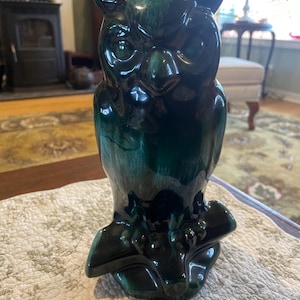 Peut inclure: Figurine de hibou en céramique avec un glaçage vert foncé brillant. Le hibou est perché sur une branche stylisée, avec des traits du visage détaillés et de grands yeux expressifs. La figurine mesure environ 30 cm de haut.