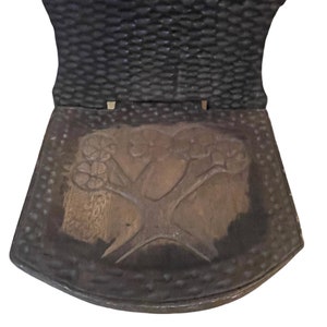 May include: A wooden chair with a carved tree design on the seat. The chair is dark brown and has a textured back.