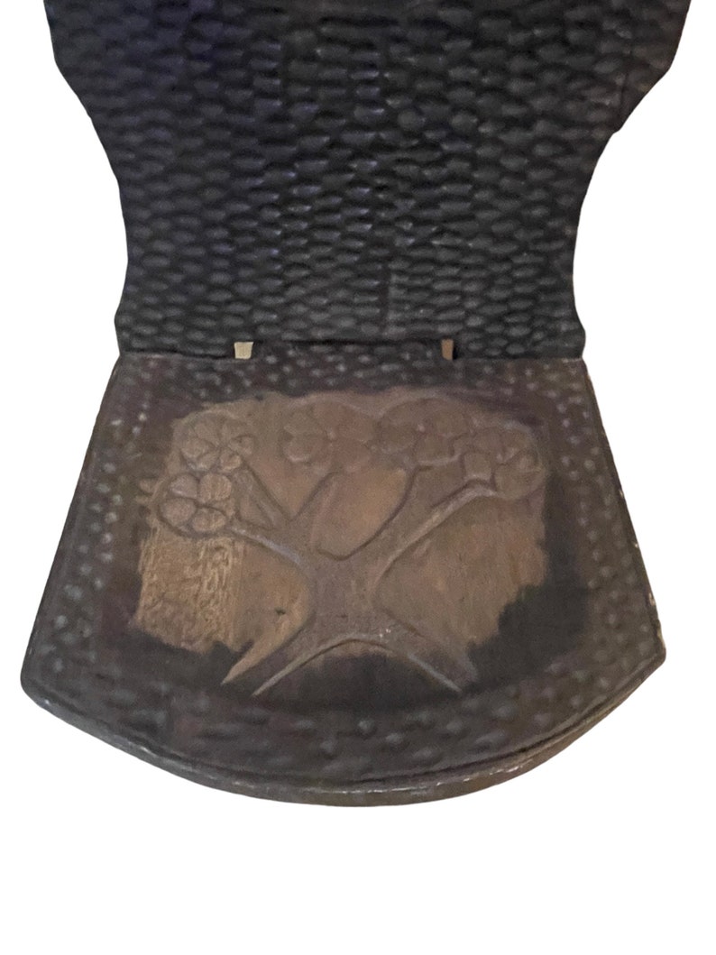 May include: A wooden chair with a carved tree design on the seat. The chair is dark brown and has a textured back.