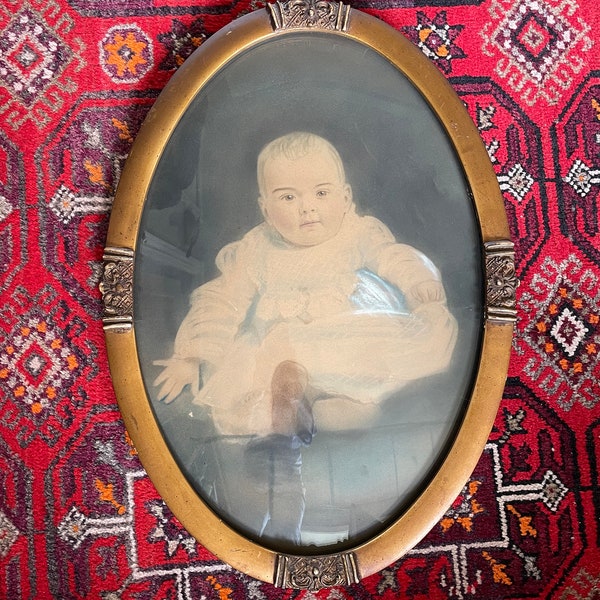 A wonderful oval convex picture frame with the original hand tinted picture of a baby circa 1800's.