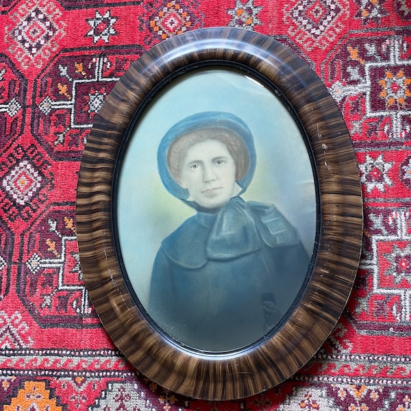 A wonderful oval convex picture frame with it's original detailed hand tinted picture of a stern lady circa 1800's.