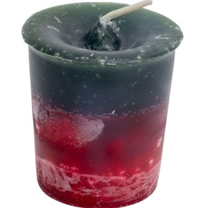 May include: A green and red votive candle with a white wick. The candle is in a glass jar.