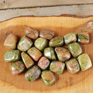 May include: A collection of tumbled green, red, and brown jasper stones. The stones are smooth and polished, and they have a variety of patterns and colors.