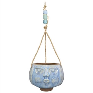 May include: A light blue ceramic hanging planter shaped like a face with a rope hanger and blue and green beads.