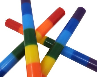 May include: Three rainbow striped candles, each with a different color at the top. The candles are arranged in an X shape, with the purple candle at the top.