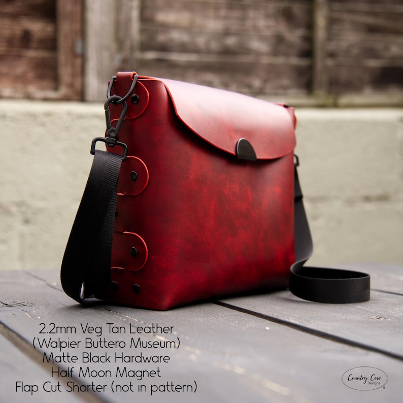 May include: A red leather crossbody bag with a black strap and black hardware. The bag has a flap closure with a half-moon magnet. The bag is made of 2.2mm veg tan leather from the Walpier Buttero Museum. "Flap Cut Shorter (not in pattern)" is written on the bottom of the image.