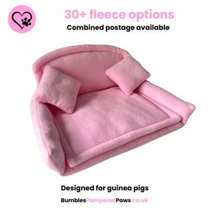 May include: A light pink fleece sofa bed for guinea pigs, with two matching pillows. The image includes the text "30+ fleece options" and "Designed for guinea pigs". The sofa is a pale pink colour.