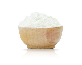 May include: A small, round, light-colored wooden bowl filled to the brim with a mound of fine, white powdery substance. The bowl has a smooth, natural wood grain texture and a rounded base, contrasting with the soft, textured white powder.