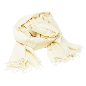May include: A cream-colored scarf with a soft, flowing texture. The scarf is draped and features fringed edges. The fabric appears lightweight and suitable for layering. The scarf is a neutral color, making it versatile for various outfits.