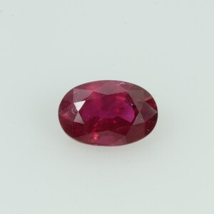Puede incluir: Una gema de rubí facetada de forma ovalada. La gema es de un color rojo intenso y saturado, con inclusiones internas visibles. La piedra se encuentra sobre un fondo blanco liso, resaltando su color y claridad. Adecuada para la fabricación de joyas.