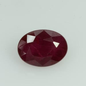 May include: An oval-shaped, faceted ruby gemstone. The ruby is a deep, rich red color with multiple facets that reflect light. The gemstone is set against a plain white background.