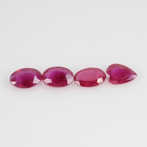 May include: Four vibrant red ruby gemstones in oval and pear shapes are displayed against a white background. The gems exhibit a rich, saturated color and a polished, reflective surface, showcasing their natural beauty and potential for jewelry design.