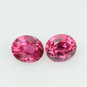 May include: Two round, faceted, hot pink gemstones with a brilliant cut. The gems are set against a plain white background, showcasing their vibrant colour and clarity. These gemstones would be suitable for jewellery.