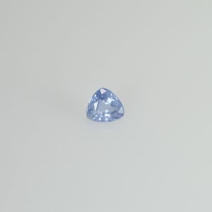 May include: A light blue, triangular gemstone with a faceted surface. The gem is set against a white background, showcasing its clarity and color. The gemstone's shape is a perfect equilateral triangle.