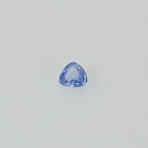 May include: A light blue, triangular gemstone with a polished surface. The gem is set against a white background, showcasing its clarity and color. The shape is a perfect equilateral triangle, ideal for jewelry.