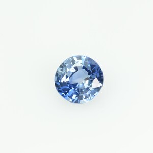 Puede incluir: Una gema azul redonda y facetada, probablemente un zafiro, sobre un fondo blanco. La gema tiene un corte brillante, que refleja la luz y muestra varios tonos de azul. Las facetas crean un efecto brillante, resaltando su claridad y color.