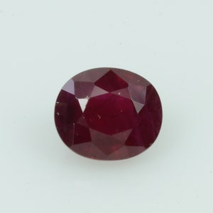 May include: A faceted, oval-shaped ruby gemstone. The gem is a deep, rich red color, with multiple facets that catch the light. The ruby is set against a plain white background.