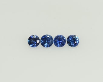May include: Four round, brilliant-cut blue gemstones are arranged in a horizontal line against a white background. The gems have facets that reflect light, creating a sparkling effect. The stones are a deep, rich blue color.