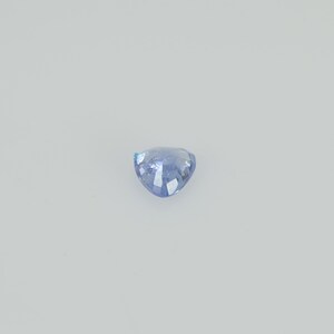May include: A light blue, heart-shaped gemstone with a faceted surface. The gem is set against a plain white background, highlighting its color and shape. The gemstone is likely a sapphire or similar precious stone.