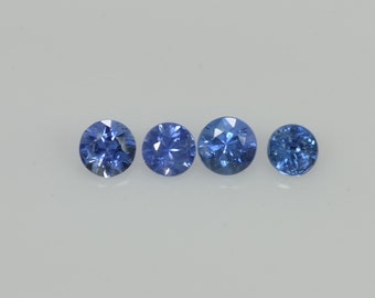 May include: Four round, faceted blue gemstones of varying sizes are arranged in a horizontal line against a white background. The gems have a brilliant cut, reflecting light and showcasing their deep blue color.