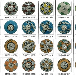 Peut inclure: Une collection de boutons de meubles d&eacute;coratifs en c&eacute;ramique de diff&eacute;rentes couleurs et motifs. Chaque bouton pr&eacute;sente un motif floral ou g&eacute;om&eacute;trique unique avec une base en m&eacute;tal. Les boutons sont &eacute;tiquet&eacute;s avec le texte "EMBOSS" suivi d'un num&eacute;ro.