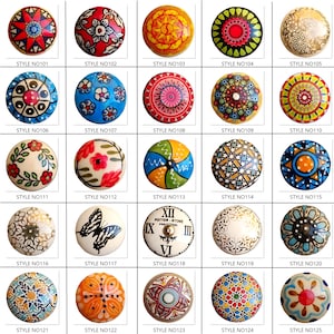 May include: A collection of decorative cabinet knobs in various styles. Each knob is round and features unique designs, including floral patterns, geometric shapes, and a butterfly. The knobs are in a variety of colors, including red, blue, yellow, and white.