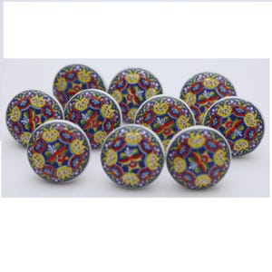 May include: A collection of ten ceramic cabinet knobs. Each knob features a vibrant, intricate design with a blue background, accented by red, yellow, and white floral patterns. The knobs are round and appear to be new.