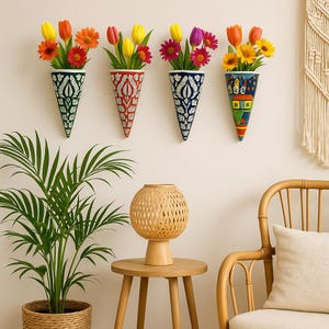 Peut inclure: Quatre vases muraux coniques avec des fleurs colorées. Les vases sont peints avec des motifs complexes en vert, rouge et bleu. Une lampe tissée et une plante en pot sont au premier plan.