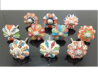 May include: A set of ten decorative ceramic cabinet knobs. Each knob is flower-shaped and hand-painted with vibrant colours such as red, orange, blue, and green. They have silver-coloured screws for attaching to furniture.
