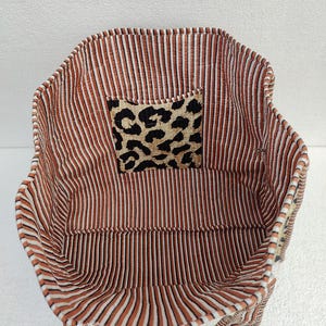 May include: Inside view of a brown and white striped tote bag with a leopard print fabric patch. The bag has two handles.