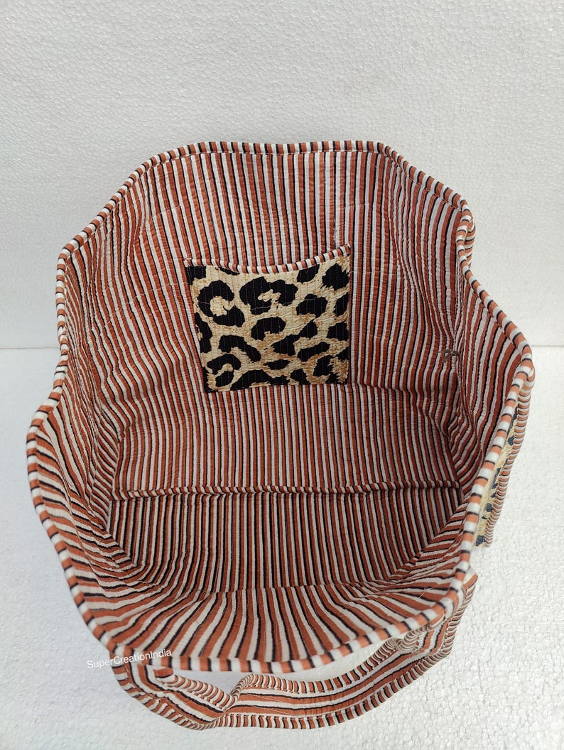 May include: Inside view of a brown and white striped tote bag with a leopard print fabric patch. The bag has two handles.