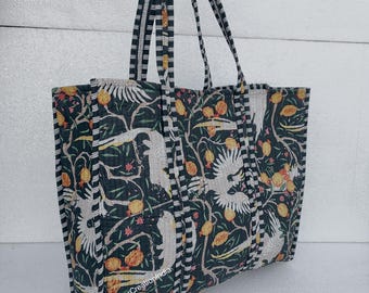 May include: A black and white striped tote bag with a floral print featuring white birds and yellow fruit. The bag has a black and white striped handle.