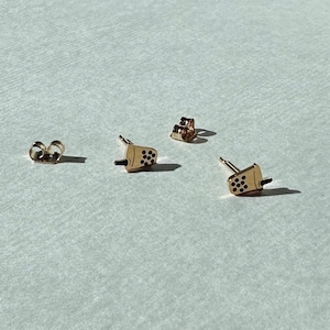 May include: A pair of gold-toned earrings featuring a boba tea design. The earrings are small and delicate, perfect for everyday wear.