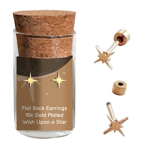 May include: Gold star shaped earrings in a glass jar with a cork lid. The jar has a label that reads "Flat Back Earrings 18k Gold Plated Wish Upon a Star".