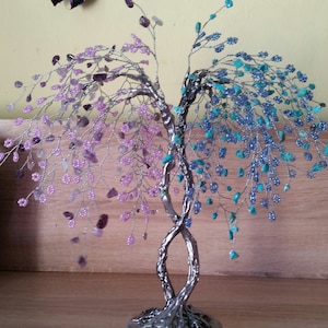 May include: A silver wire tree sculpture with pink, blue, and turquoise beads. The tree has two trunks that twist together and a round base.