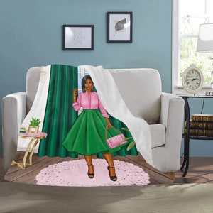 Op de afbeelding: Een wit deken met een groene en roze illustratie van een vrouw die voor een raam met groene gordijnen staat. De vrouw draagt een roze shirt, een groene rok en houdt een roze handtas vast.